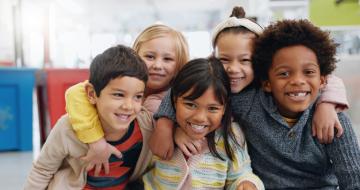 Five elementary students gathered together smiling for the camera.